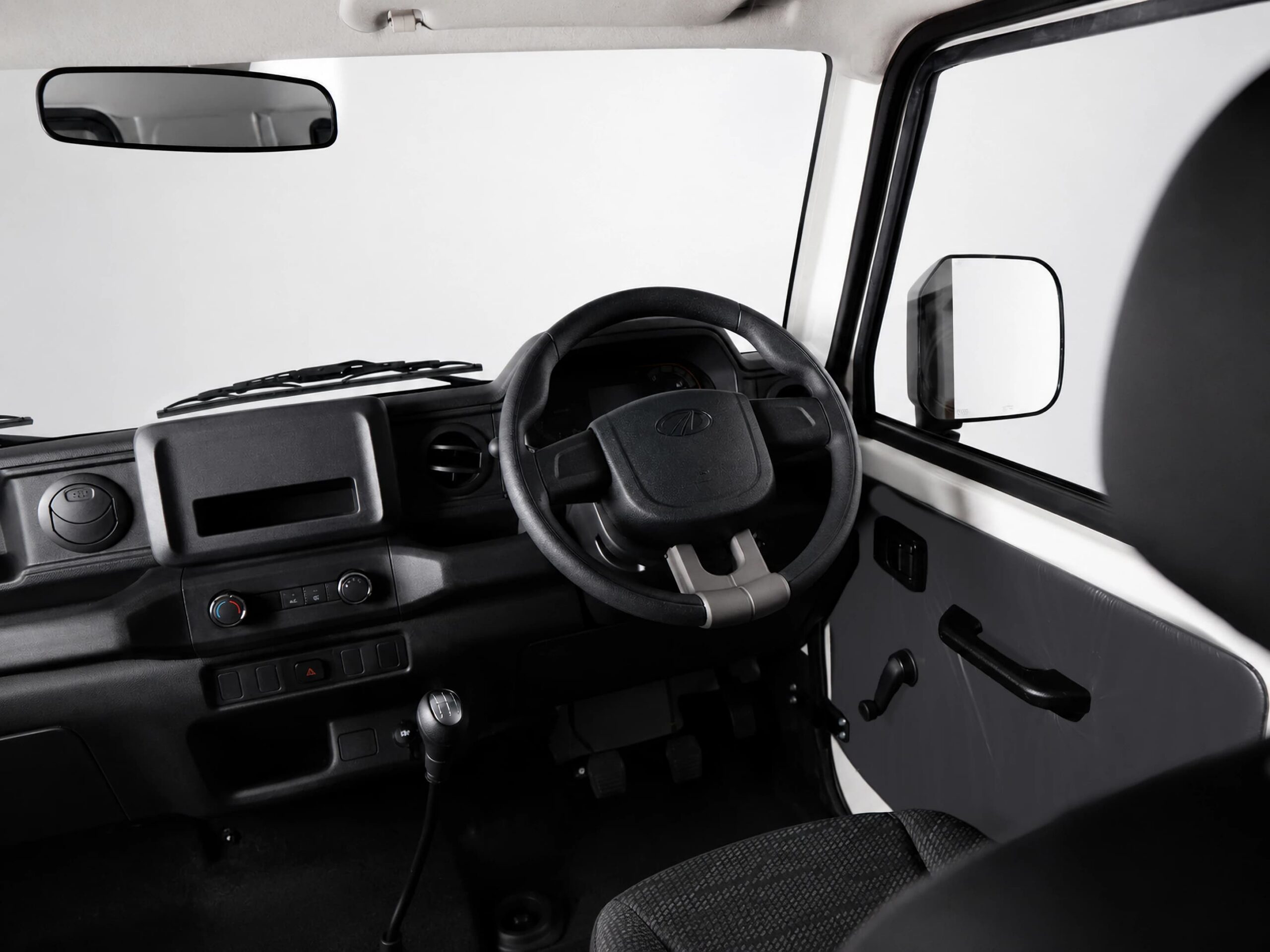 Driver's cockpit of a vehicle showing the steering wheel, dashboard, gear lever, and side mirror. (monochrome)